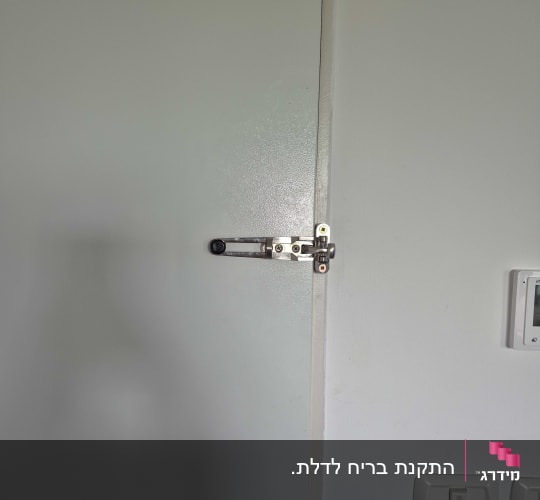 מנעול דלת עם בריח מתכת על דלת לבנה